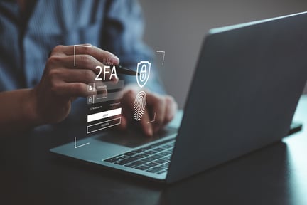 A 3D cybersecurity icon with a 2FA login projected above a laptop.