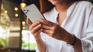 A woman holding and using a new Apple iPad Pro digital tablet in a cafe.