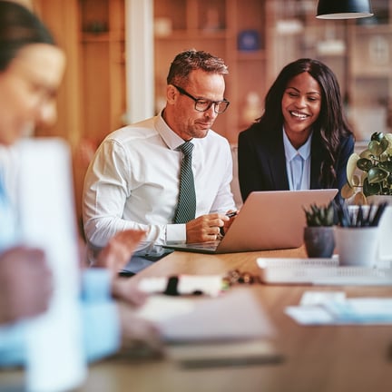 Managed IT services consultant discussing business IT solutions with a happy client during a meeting, showcasing expert support.