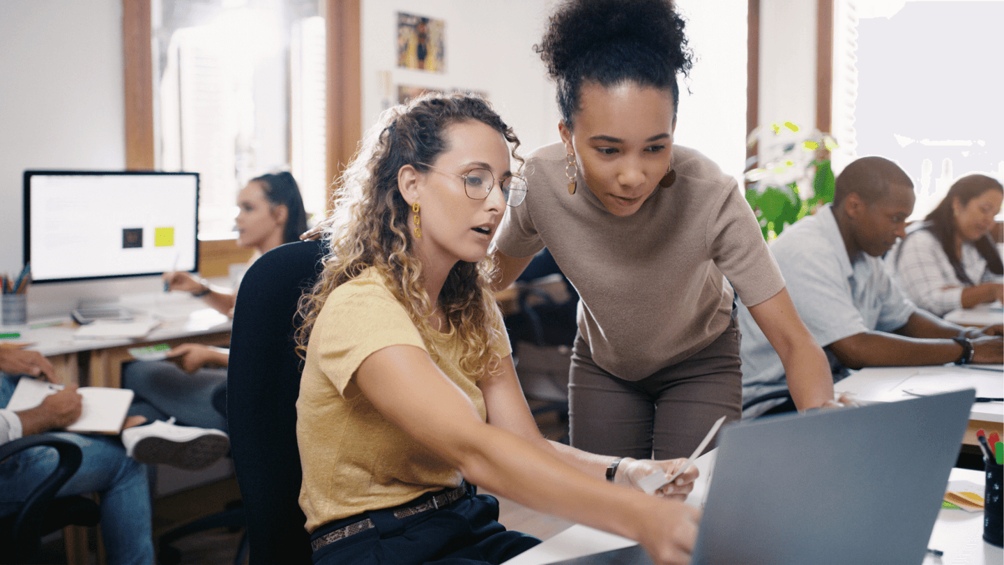 A female employee shares an IT spending issue with her manager using a laptop.