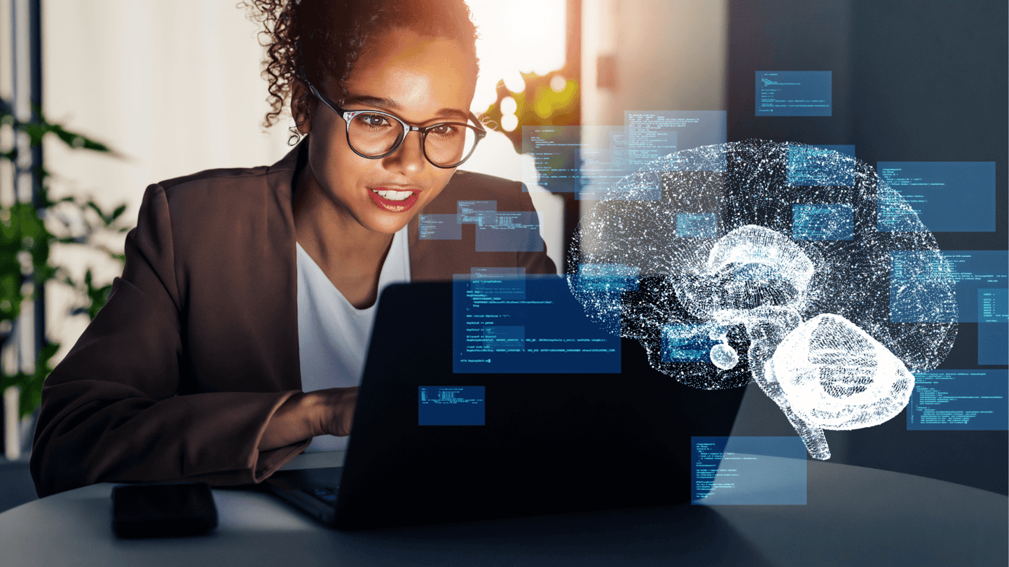 A holographic image demonstrating AI displayed in front of a female employee using a laptop.