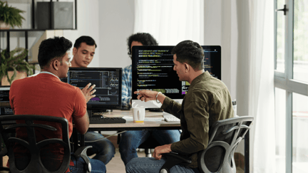 Developers review lines of code on computer in an office.