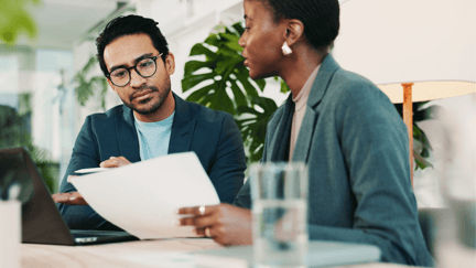 Two employees review contracts for IT investments in an office. 