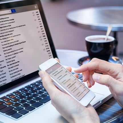 Business person reading emails on smartphone and laptop computer screen