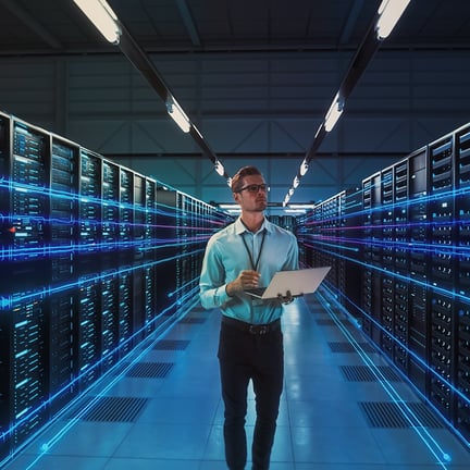 chief information officer standing amongst servers in data center holding laptop
