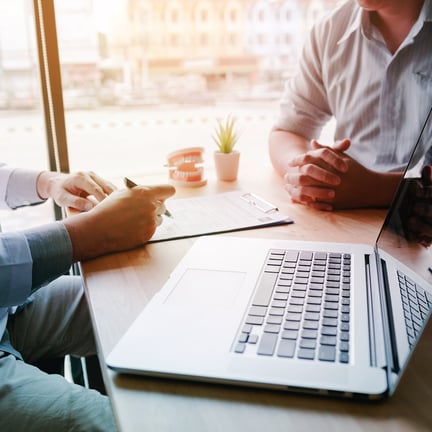 dentist seated at desk discussing treatment with patient