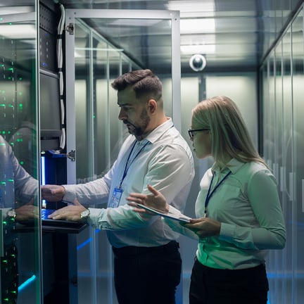 pair of technicians using tablet and laptop while diagnosing server hardware in a modern data center