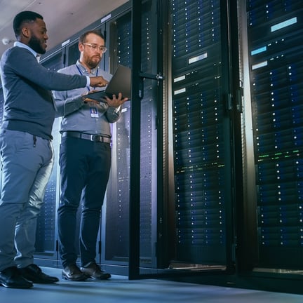 two IT professionals standing next to servers performing data center management