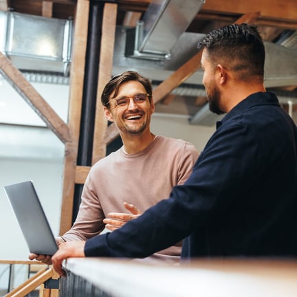 Two IT consultants having lighthearted discussion over laptop