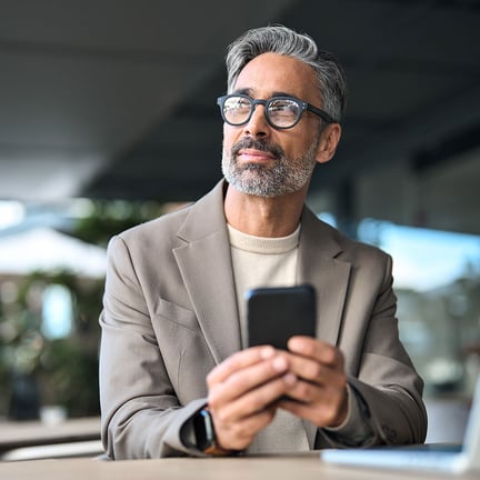 business executive seated outside holding mobile device deep in thought contemplation