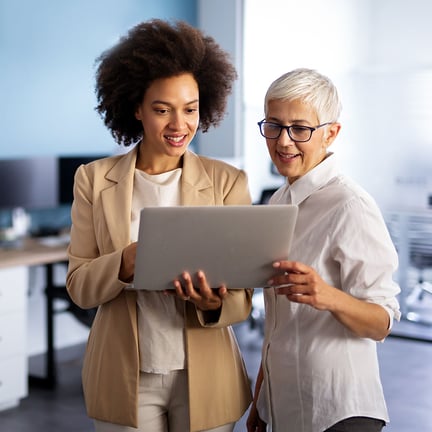 Happy smiling business women working together online on a laptop in an office