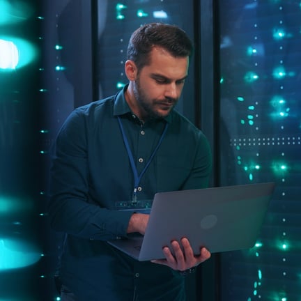 IT professional admin using laptop computer doing data transfer operation with rack server cabinets in digital room of data center