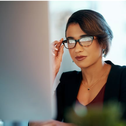businesswoman with french manicure peering through eyeglasses lenses reflecting computer monitor screen