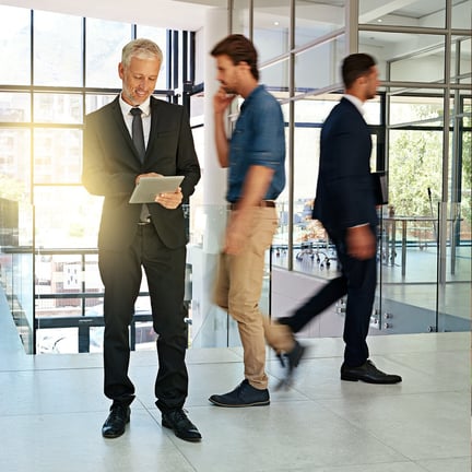 business executive smiling holding tablet surrounded by motion blur of colleagues
