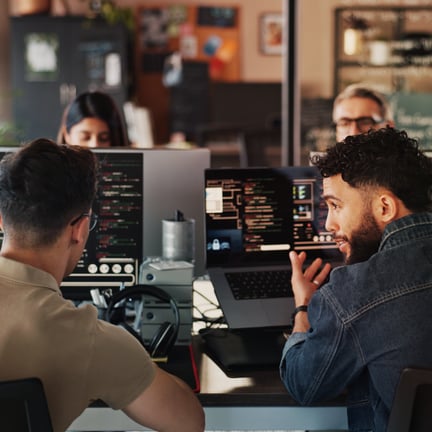 software developers having discussion seated at screens showing computer code