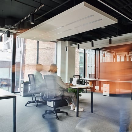 motion blur of person walking in open concept office environment with two workers seated at desk