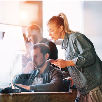 office workers dressed casually collaborating at desk using digital devices