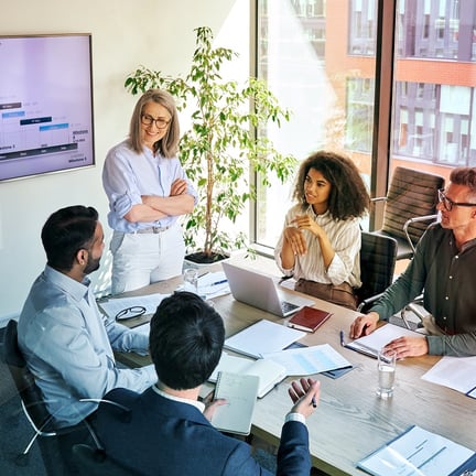 colleagues seated at boardroom table headed by female executive