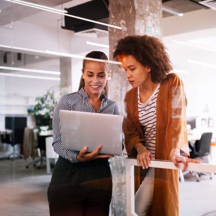 two professionals looking at laptop screen in corporate office
