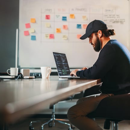 Young professional wearing wired earphones engaged in software development at an open office