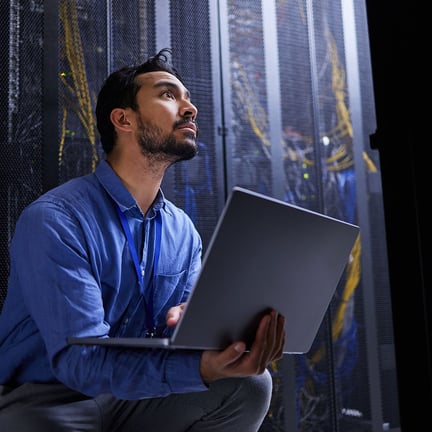 engineer holding laptop in server room executing on-site IT support services