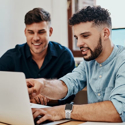 two smiling colleagues collaborating over laptop