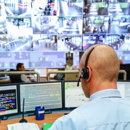 security guards working on computers while sitting in the main control room