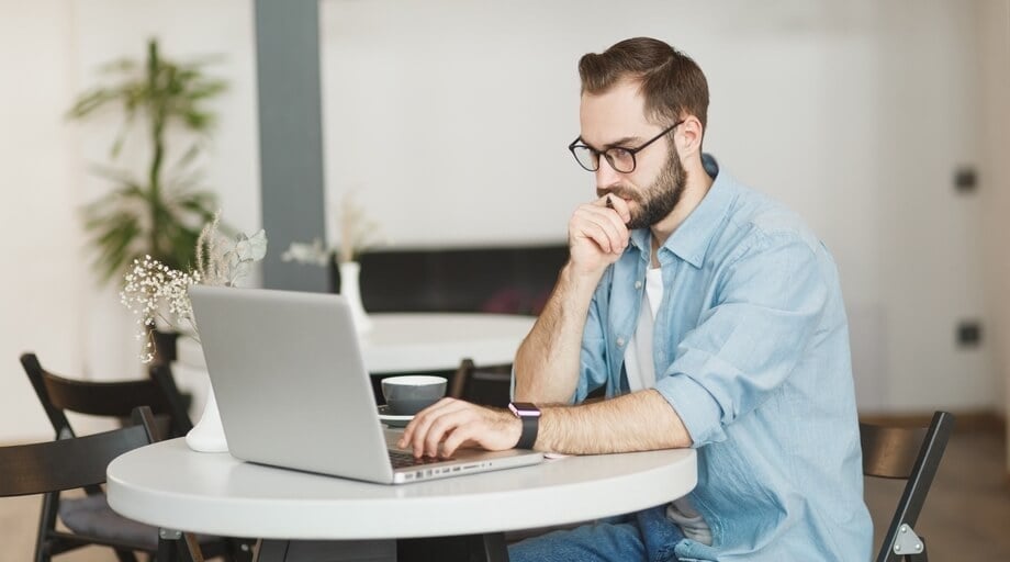 A man working on his laptop remotely at a cafe