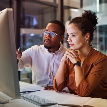 IT support specialist assisting a professional with technical analysis on a desktop computer for business IT solutions.