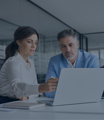 Two attorneys review data on a laptop together. 