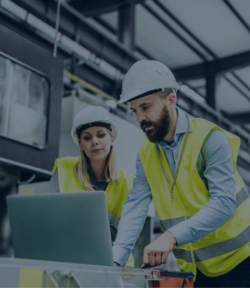 Manufacturing workers review information on a computer.