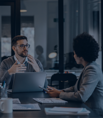 Private equity firm employees discuss financial data during a meeting.